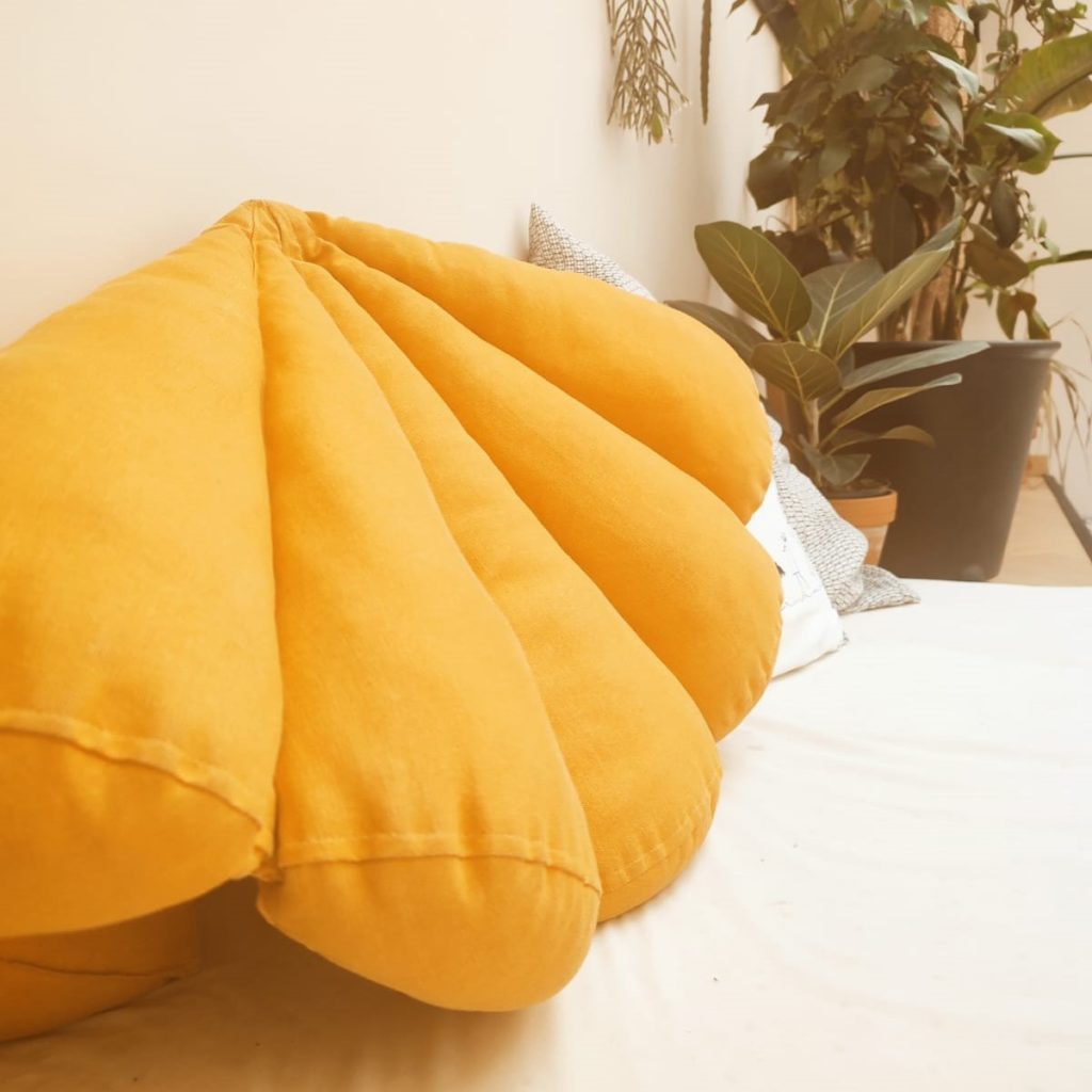 Coussin jaune au premier plan. Plantes en arrière plan.