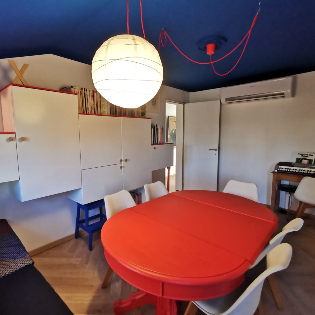 Salle de jeux enfant. Plafond bleu roi, table et luminaire rouges.