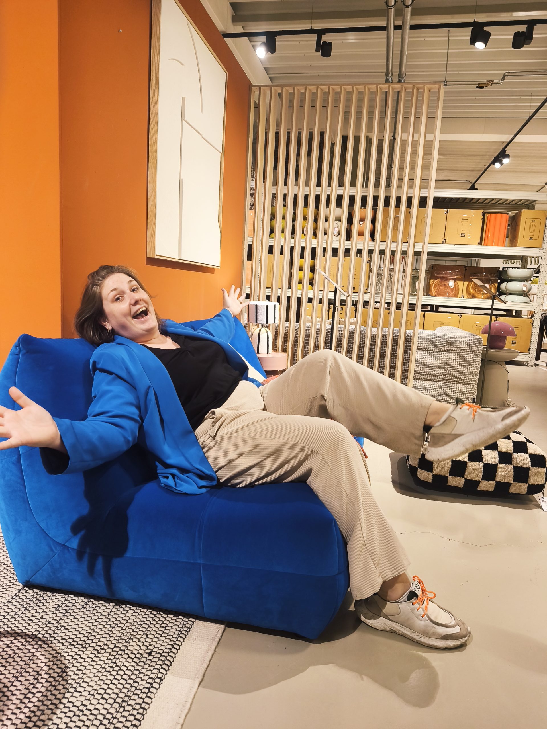 Marine assise dans un fauteuil bleu avec un grand sourire et un regard espiègle